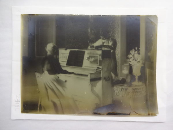 Dr Baker standing behind a piano with his sister/wife playing