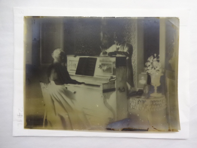 Dr Baker standing behind a piano with his sister/wife playing