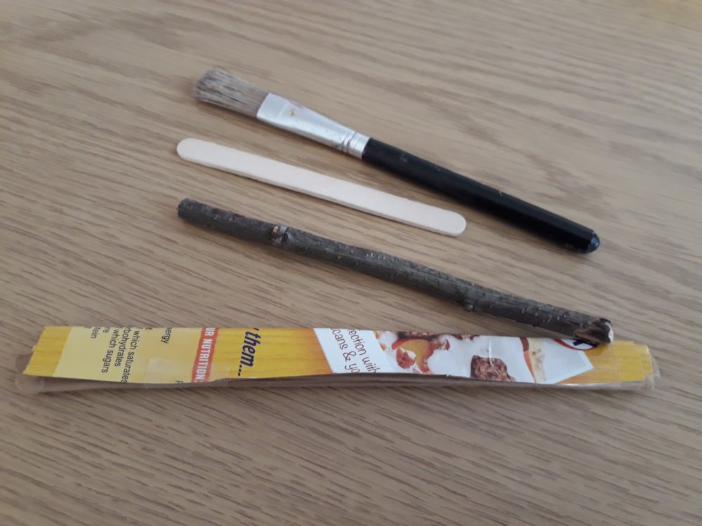 A paintbrush, a lollipop stick, a twig and cardboard