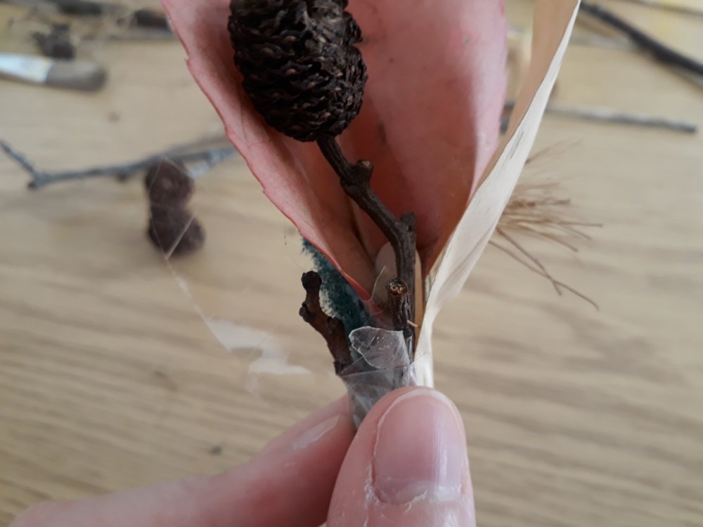 A hand holding a lollipop stick with some materials stuck onto the end of it