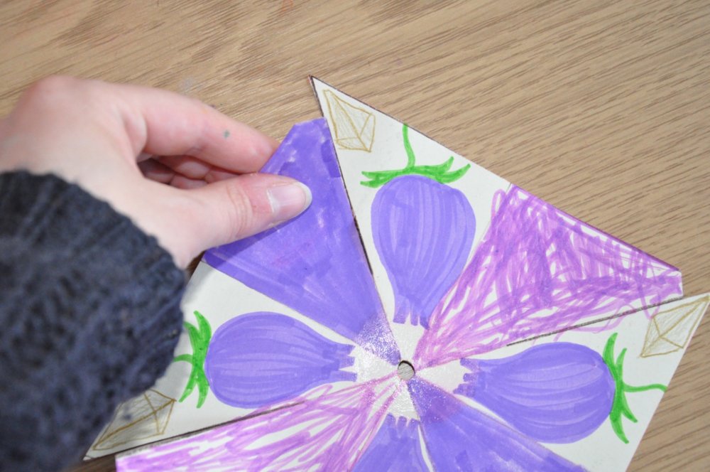 A hand holding a flap of the flower wheel.