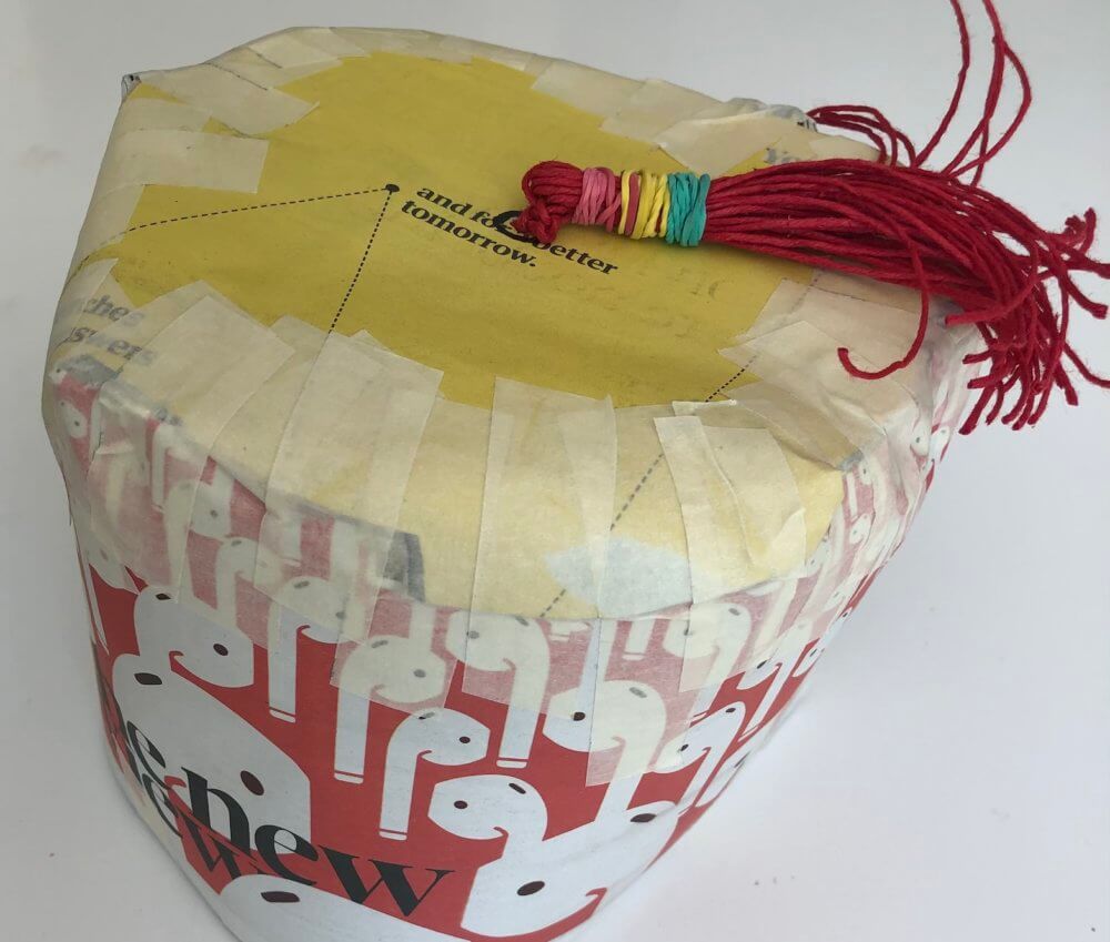 A Fez made from a newspaper, tape, string and elastic bands