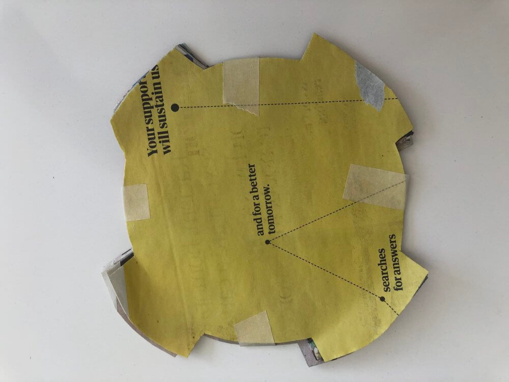 Masking tape attaching the circular cut newspaper together