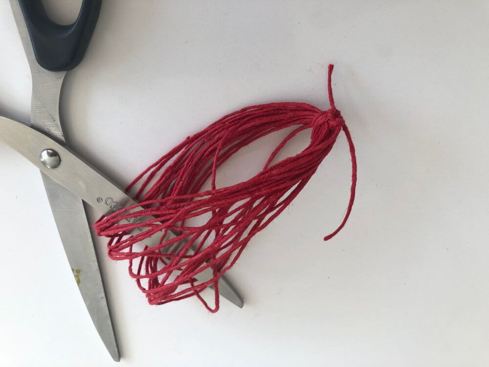 Scissors cutting the string (removed from the tape) to create a tassel