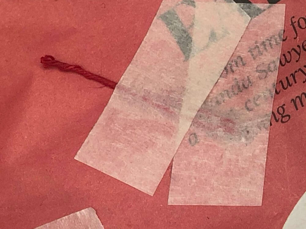 Tape over the string that is poking through the newspaper hole to keep it in place