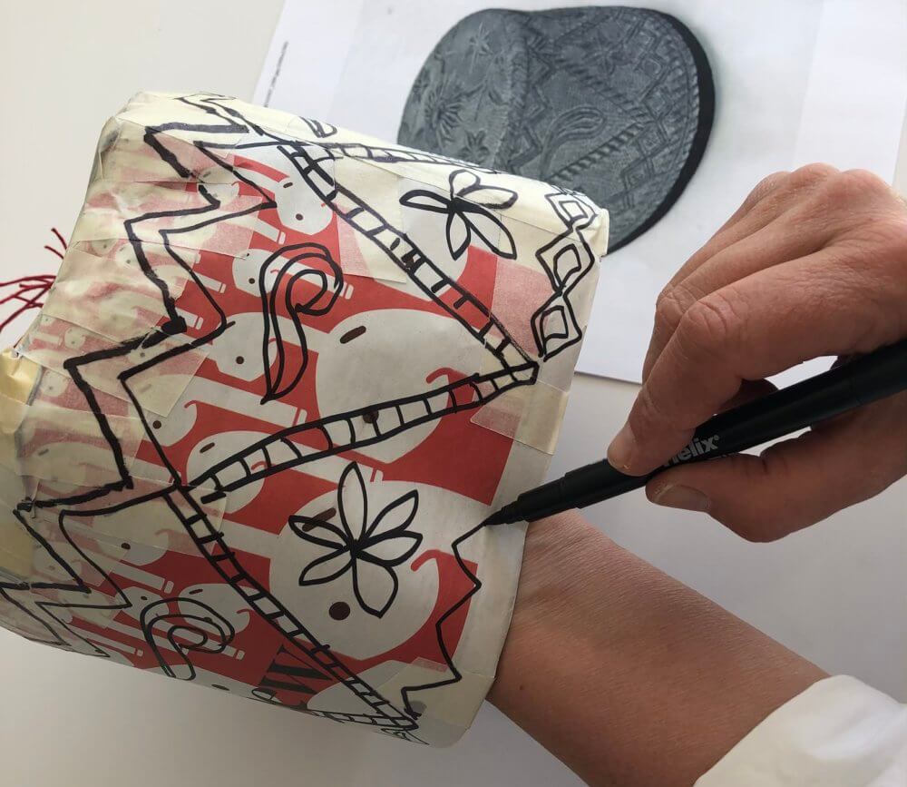 Hand decorating the outside of the hat with a pen