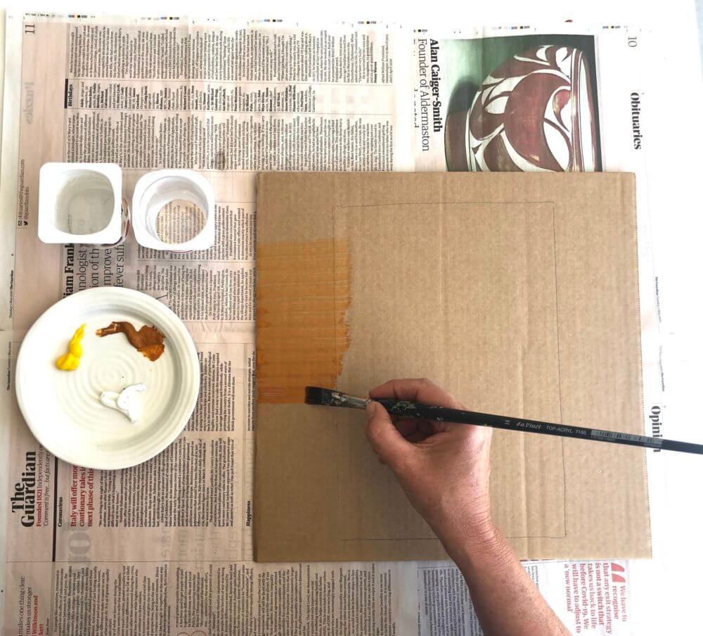 Someone painting a carboard square